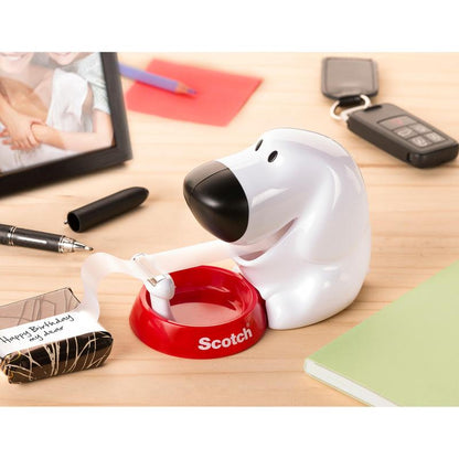 The Scotch™ desktop dispenser in dog design C31 with Scotch® Magic™ invisible tape (19 mm x 8.89 m, 1 roll/package) by 3M Deutschland GmbH sits on the desk between office supplies like a notebook and marker.
