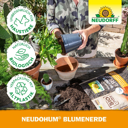 A person repotting a plant at a table with soil, potted garden plants, gardening tools, potting soil bags, and a NeudoHum potting soil bag from Neudorff Shop. Next to the Neudorff logo, symbols for environmental friendliness and pet-friendliness appear.