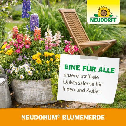 A metal bucket with colorful garden plants stands on a garden path next to a wooden folding chair. A sign advertises the peat-free NeudoHum potting soil from Neudorff Shop for indoor and outdoor use.
