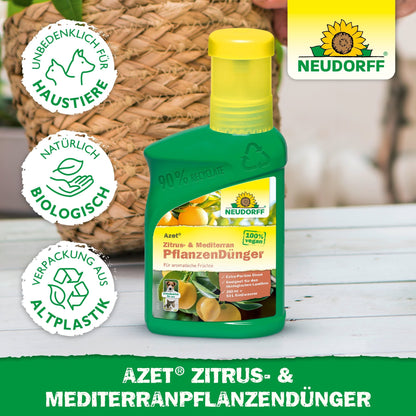 A green bottle of Neudorff Shop Azet Citrus & Mediterranean Plant Fertilizer for Mediterranean container plants stands on a table, with visible label and surrounding symbols indicating pet safety, natural ingredients, and recycled packaging.