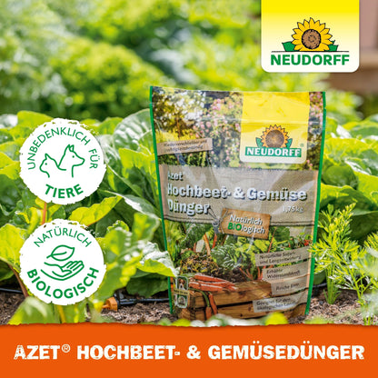 In the vegetable garden, there is a bag of Azet Raised Bed & Vegetable Fertilizer from Neudorff Shop, an organic fertilizer for vegetables and herbs. Labels indicate animal-friendly, natural, and organic quality. Green plants and soil are visible.