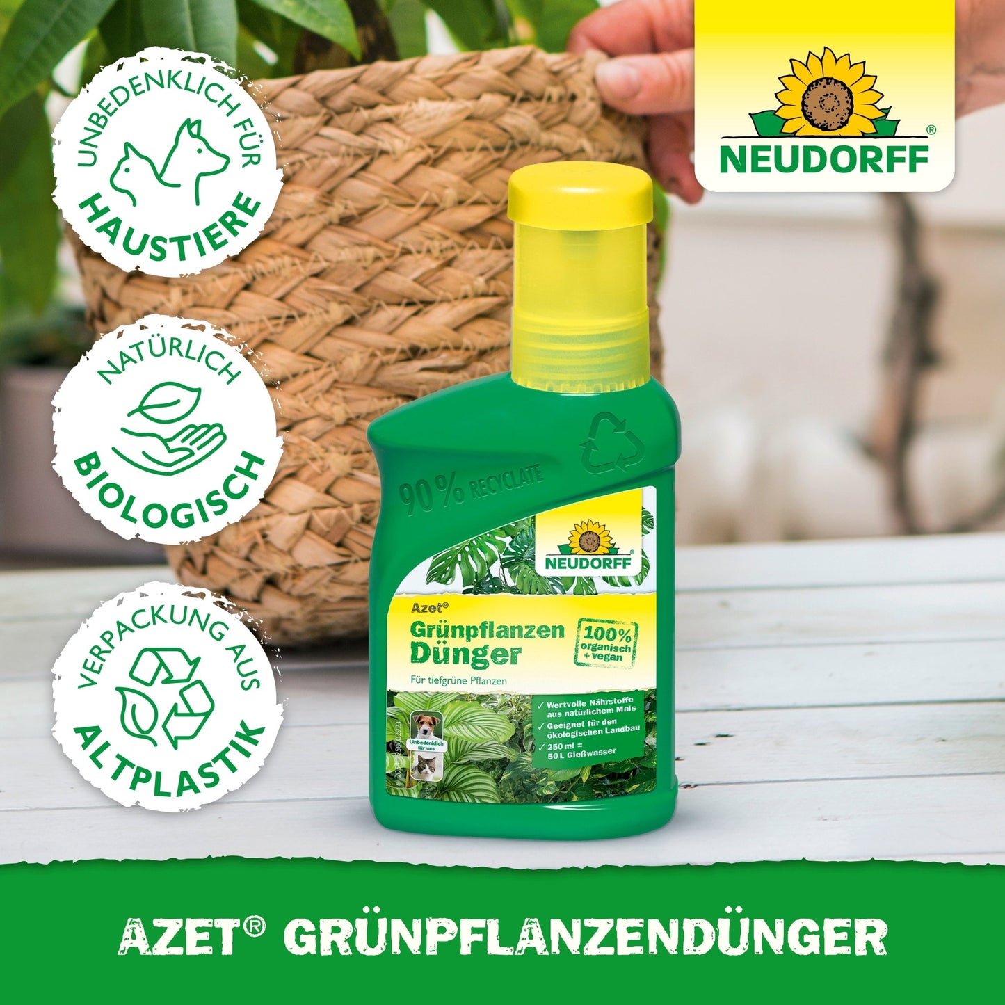 A green bottle of Neudorff Shop Azet Green Plant Fertilizer liquid stands on a table next to a potted plant. The label lists nutrients for green plants, pet safety, natural ingredients, and recycled packaging. A hand is visible in the background.