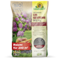 A 20 kg bag of Neudorff's UrgesteinsMehl from the Neudorff Shop, depicted with purple flowers, carrots, and soil images. The bag with German text covers 200 m² and contains mineral powder for use in the soil.
