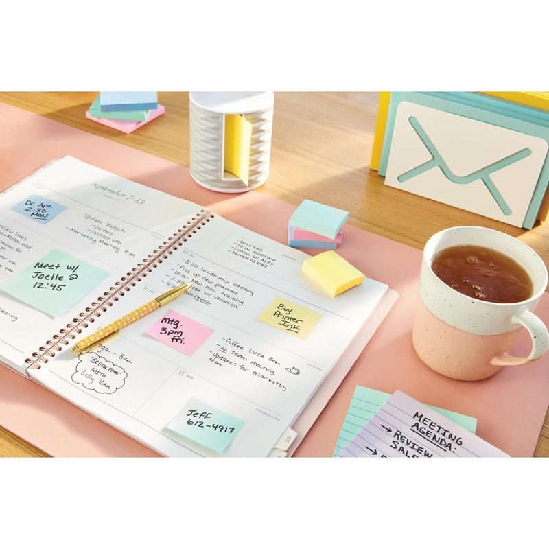 An open planner with handwritten notes lies on a desk next to a cup of tea, index cards, a pen, and Post-it® Notes in Yellow (38 mm x 51 mm, 3M Deutschland GmbH) as well as a container.