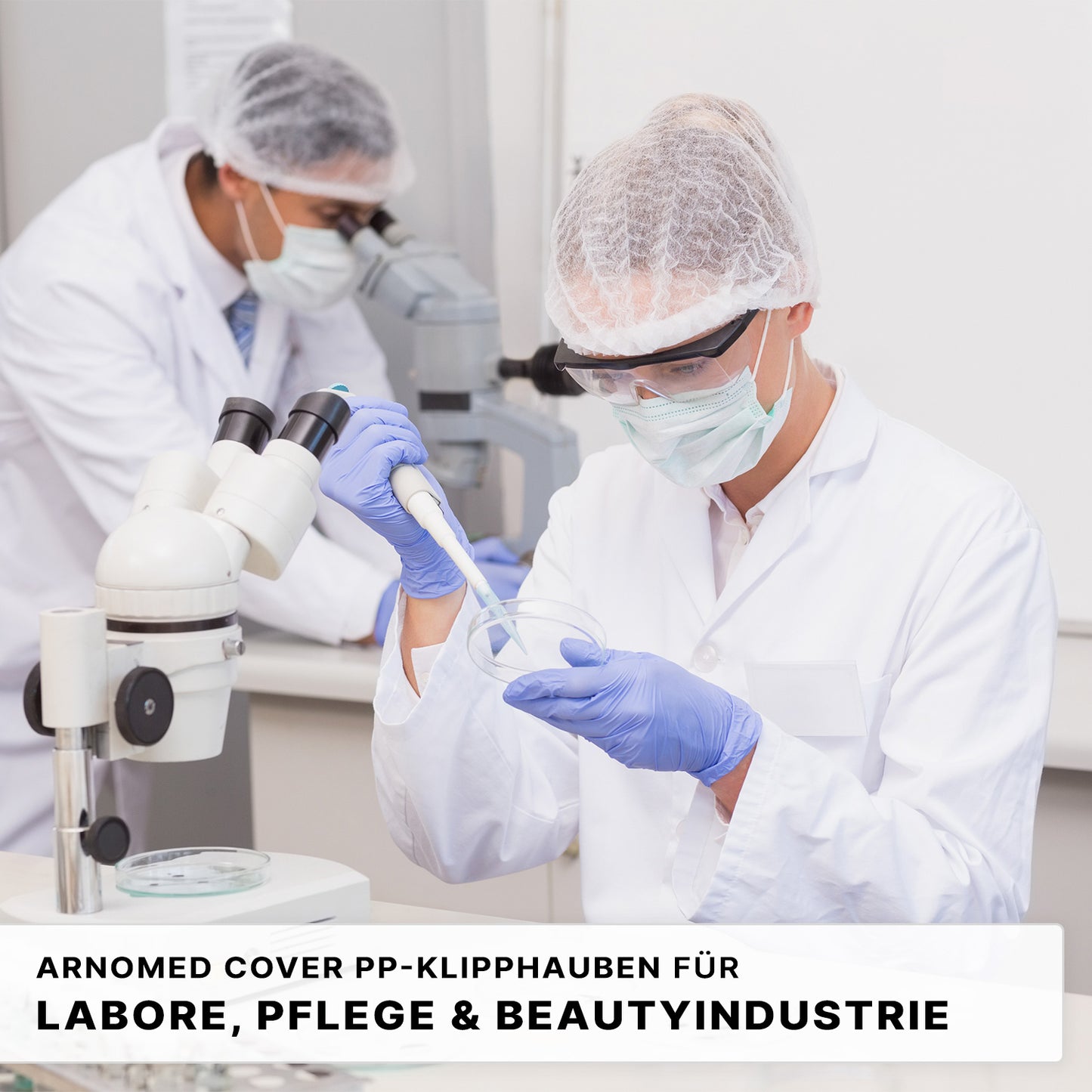 Two people in white lab coats, with ARNOMED COVER PP-CLIP CAP XL hair ties from ARNOWA GmbH, face masks, and safety goggles work in a lab; one uses a pipette, the other looks into a microscope. The German hygiene regulations are shown below.