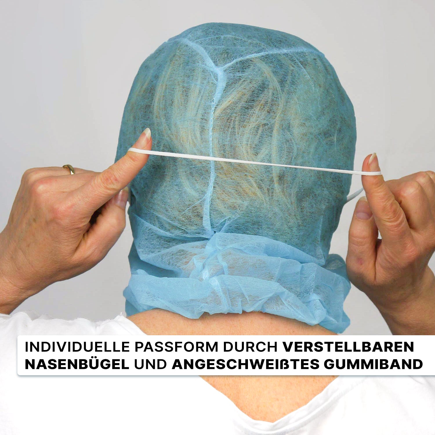 A person puts on a blue ARNOMED COVER PP-ASTROHAUBE WITH 2-LAYER MOUTH PROTECTION from ARNOWA GmbH with a rubber band on their head, equipped with an adjustable nose clip. German text highlighting the features appears at the bottom.