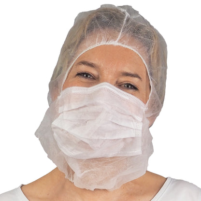 An adult wearing the ARNOMED COVER PP-ASTROHAUBE WITH 2-LAYER MOUTH PROTECTION from ARNOWA GmbH and a white surgical mask over mouth and nose stands against a plain white background.