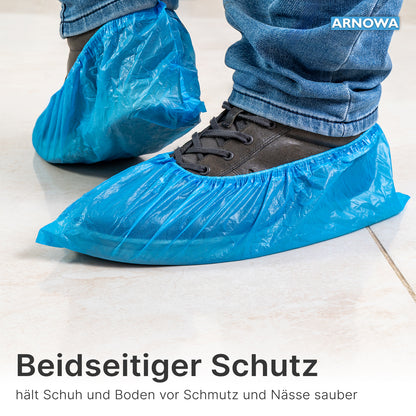 A person wears ARNOMED CPE shoe covers from ARNOWA GmbH over dark shoes on light tiles. At the edge of the image, protection for shoes and floors from dirt and moisture is advertised. Bag with 100 pieces, waterproof, disposable.