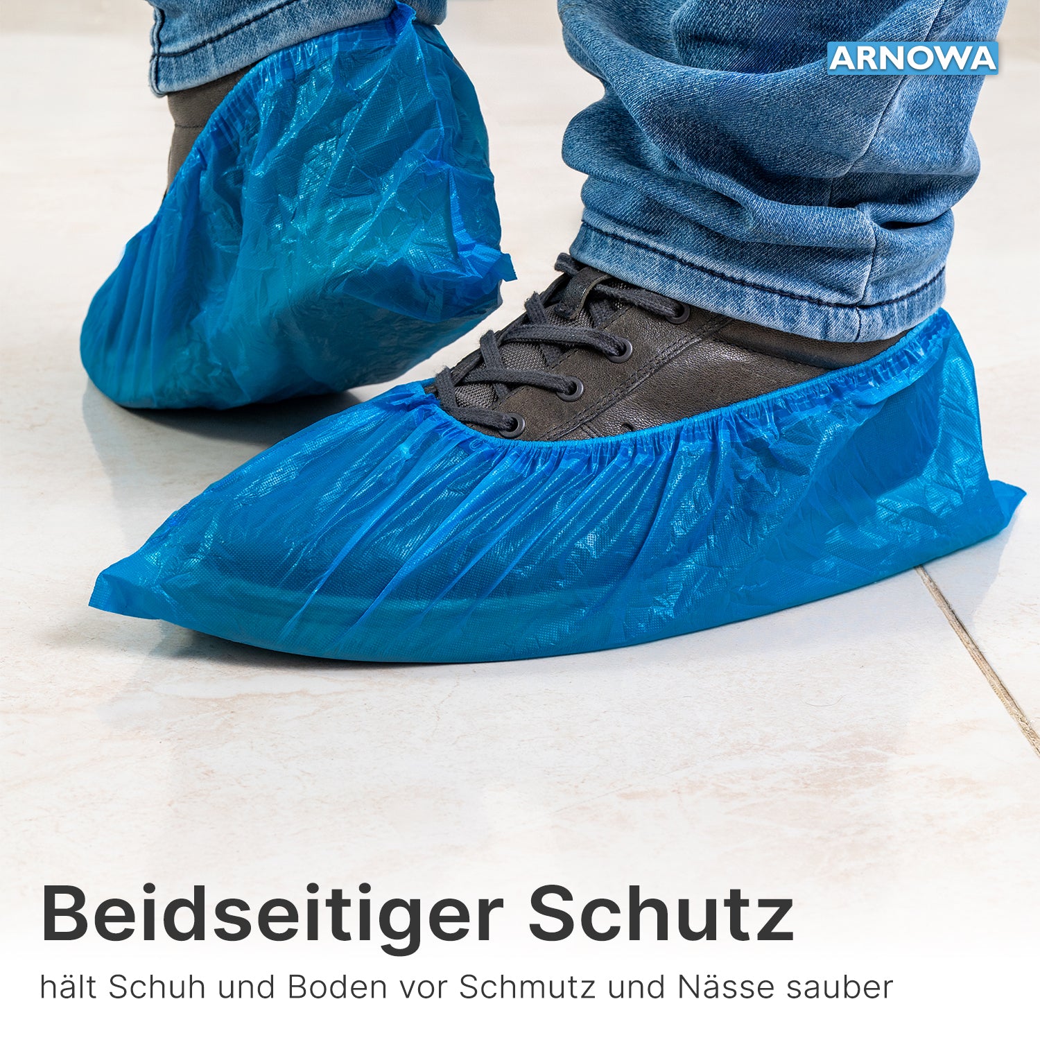 Close-up of a person with ARNOMED Xtra Strong CPE shoe covers from ARNOWA GmbH over dark shoes and jeans. The waterproof disposable covers reliably protect shoes and floors from dirt and moisture. Bag of 100 pieces.