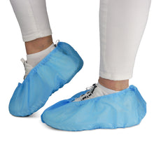 A person is wearing white pants and sneakers with ARNOMED ABS shoe covers from ARNOWA GmbH. The non-slip disposable covers (bag of 100 pieces) protect shoes and floors - ideal for hygienic environments.