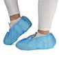 A person is wearing white pants and sneakers with ARNOMED ABS shoe covers from ARNOWA GmbH. These non-slip, disposable shoe covers (pack of 100) protect shoes and floors—ideal for hygienic environments.