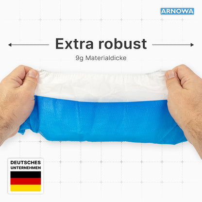 Two hands hold a blue-white ARNOMED CPE/PP disposable shoe cover (waterproof, 50 pieces, ARNOWA GmbH) with the inscription "Extra robust" and "9g material thickness". In the corners there is a German flag, "GERMAN COMPANY" and the ARNOWA logo.