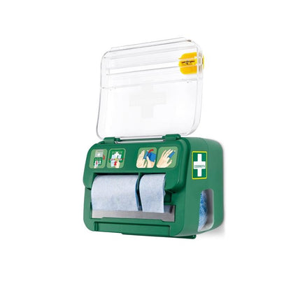 The green, wall-mounted Cederroth Soft Foam Bandage 2-in-1 Dispenser from Orkla Wound Care AB holds six bandages, features a transparent lid with a cross symbol, blue paper rolls, illustrated instructions, and a yellow emergency wound care tool on top.
