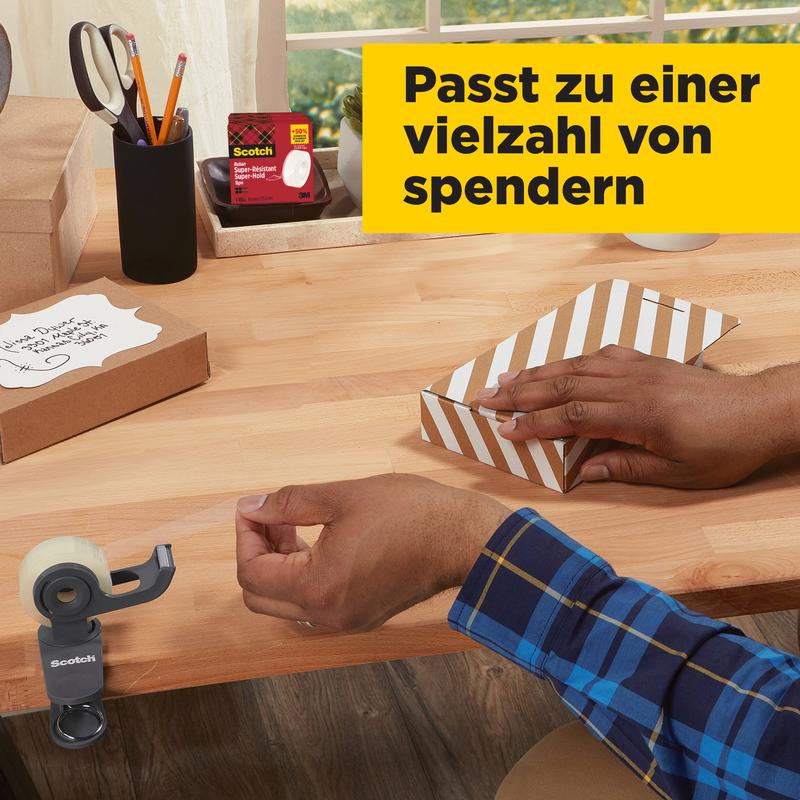 A person in a blue checkered shirt tapes a striped box with Scotch® Super-Hold Secure Tape, 1 roll, 19 mm x 25.4 m from 3M Deutschland GmbH on a wooden desk with office supplies and gifts; German text is displayed in a yellow box.