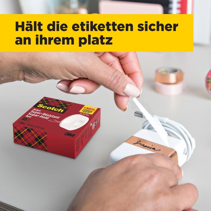 A person wraps a white label with black writing around a white charger while a box of Scotch® Super-Hold Secure Tape, 1 roll, 19 mm x 25.4 m from 3M Deutschland GmbH stands on the table. In the background, blurred office materials and a yellow German flag can be seen.