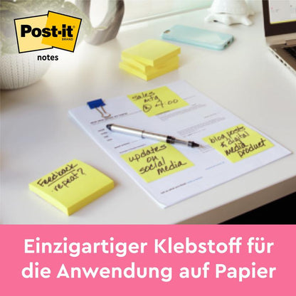 A stack of 3M Post-it® Notes, yellow (76 mm x 127 mm, 100 sheets/block), lies on a desk next to notes. Text below: "Strong adhesive - sticks securely to paper. 12 blocks per pack, cardboard packaging, 100% PEFC.