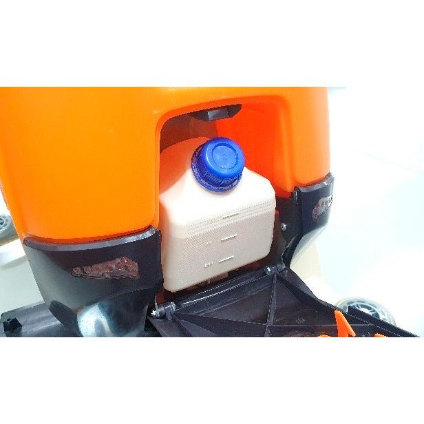 A close-up of the Ultimaxx Intellidose+ canister from Diversey Deutschland GmbH & Co. OHG shows the white square container with a blue screw cap in an orange compartment, surrounded by black and metallic parts.