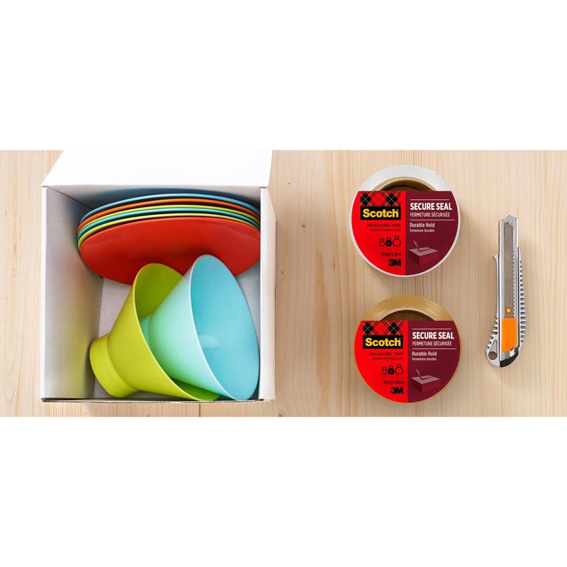 On the left is a cardboard box with stacked colorful plastic plates and bowls. On the right are two rolls of 3M Deutschland GmbH Scotch® packaging tape for secure sealing (50 mm x 50 m) and a utility knife on wood.