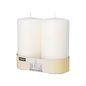 Two large, white Starpak pillar candles (Ø 80 mm) with flat top and unlit wick stand side by side in a beige and white Starpak packaging.