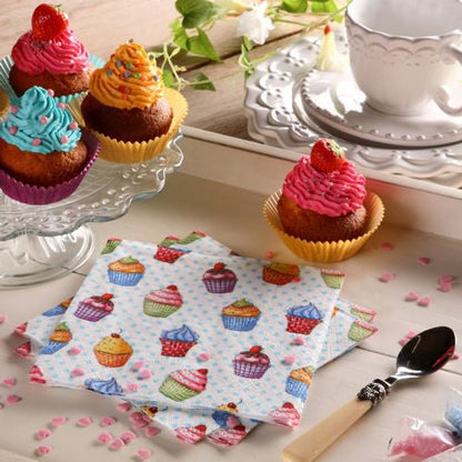 A table is set with cupcakes on a glass stand, a plate, spoon, white teacup and saucer, pink heart-shaped sprinkles, and colorful PAPSTAR 20 napkins 33x33cm 3-ply 1/4-fold design set 5 by PAPSTAR GmbH.