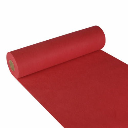 A roll of Starpak table runner, fabric-like fleece "Soft Selection" (24 m x 40 cm), is partially unrolled on a white surface, the roll is on the left and the red runner extends to the lower right corner.