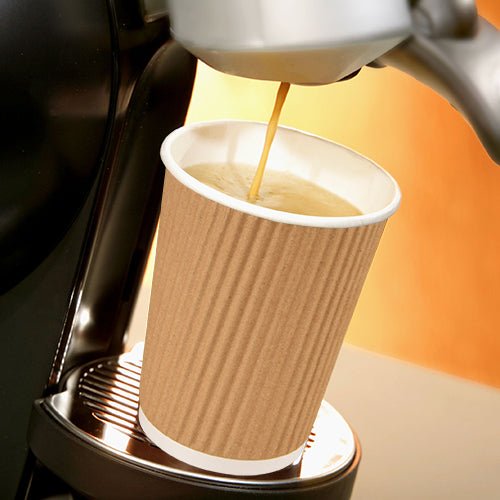 Coffee is dispensed from a machine into a brown PAPSTAR 25 drinking cup paper "To Go" Ripple Wall from PAPSTAR GmbH, which is placed on a metal drip tray.