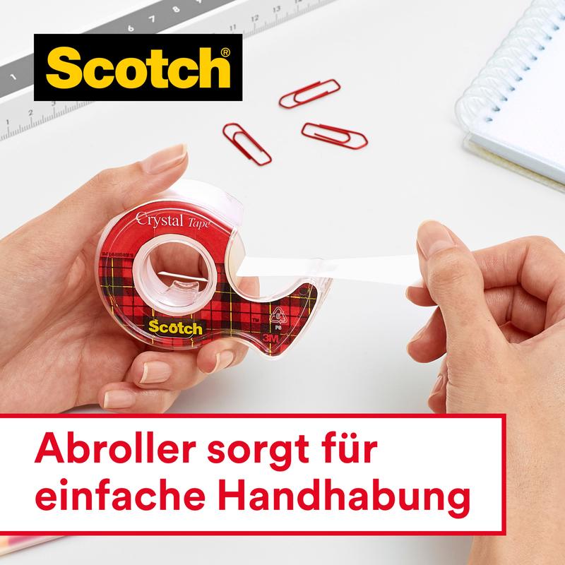 A person pulls Scotch® Crystal Tape, transparent, 19 mm x 33 m, by 3M Deutschland GmbH from a red tartan dispenser. Nearby: red paper clips, ruler, spiral notebook. German text below: "Dispenser ensures easy handling."