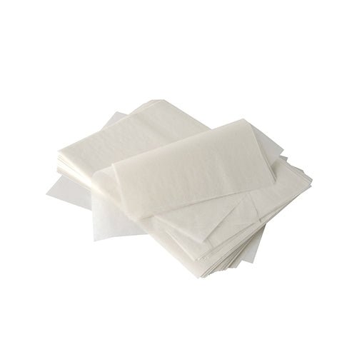 A stack of semi-transparent PAPSTAR cream cover paper "pure" (32x22 cm, white, palm wax coating, 1000 pieces) from PAPSTAR GmbH lies on a white surface - perfect for use in gastronomy; some sheets are flat, others folded or overlapping.