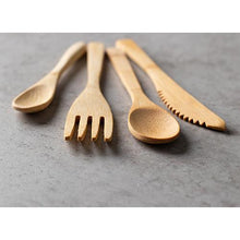 Ten environmentally friendly PAPSTAR bamboo forks "pure" (16.5 cm) from PAPSTAR GmbH are spread out side by side on a gray surface.
