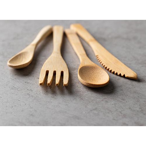 Four PAPSTAR bamboo spoons "pure" (16.5 cm, environmentally friendly and sturdy) stand side by side on a gray, textured surface, offering a sustainable dining solution from PAPSTAR GmbH.
