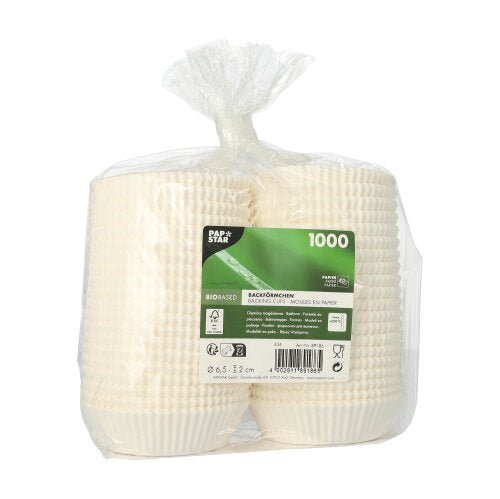 A transparent plastic packaging contains four stacks of paper baking cups "PAPSTAR 1000 baking cups round" of PAPSTAR GmbH with a green label indicating 1000 pieces, information about the bio-based material, and other product details.