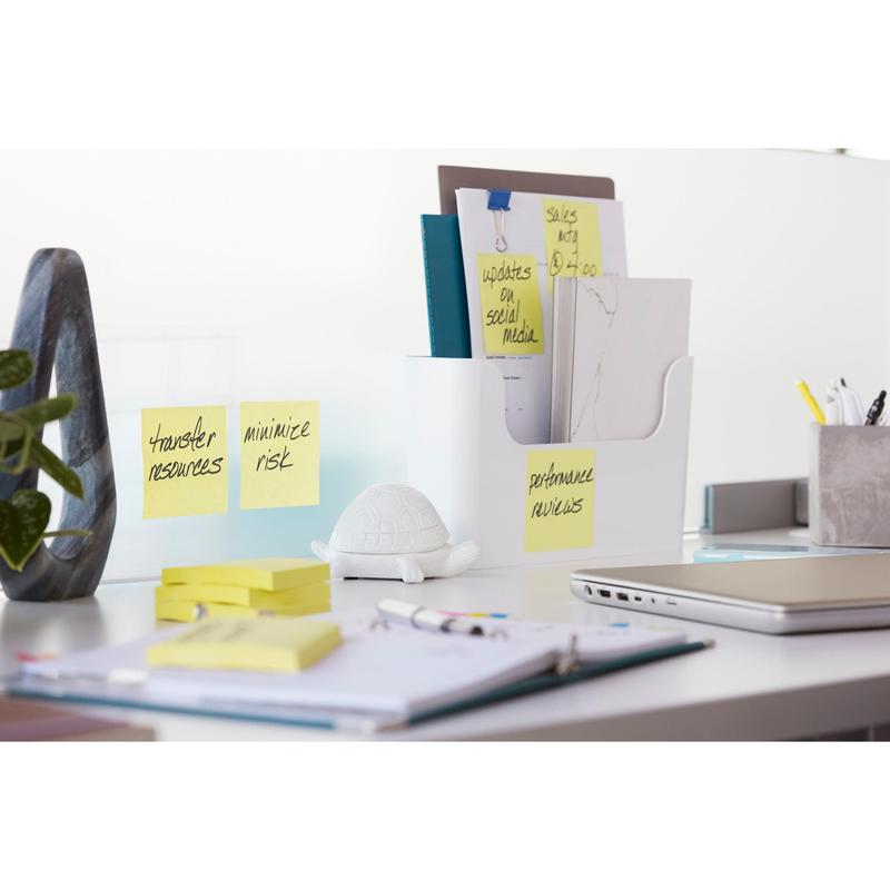 On a modern desk are folders, notebooks, a white turtle figure, a closed laptop, and Post-it® Super Sticky Notes (47.6 mm x 47.6 mm, 90 sheets/block, 100% PEFC) from 3M Deutschland GmbH with notes like "Transfer resources" and "Performance review."