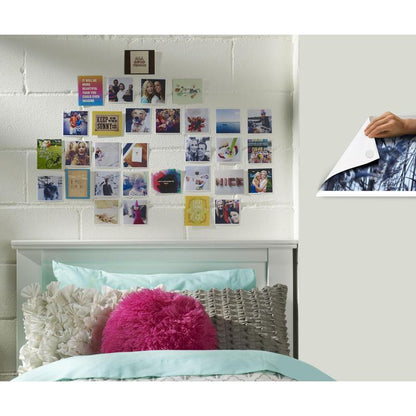 A white bed with teal and white bedding stands in front of a white brick wall. Above it are small photos arranged in a grid with Scotch-FIX™ Removable Adhesive Pads 301008C36-P from 3M Deutschland GmbH - strong hold, easy removal.