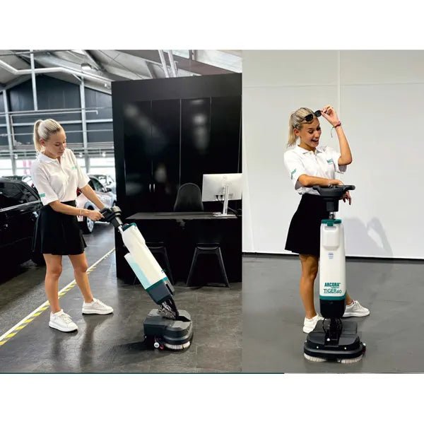 Two women in white shirts and black skirts use the Arcora International GmbH Tiger 40 floor cleaning machine | Carton (1 piece) indoors; one operates the machine while the other smiles and presents their professional cleaning.