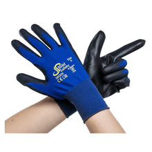 A pair of crossed arms with ultra-light blue and black safety gloves AMPri SolidSafety Tough Fine Touch exudes premium quality. The open palm of the left glove faces forward, while the right forms the shape of a finger gun. These gloves proudly display the logo of AMPri Handelsgesellschaft mbH and size information from XS to XXL, ensuring reliable performance.