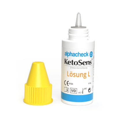 Next to it stands a white bottle of Alphacheck KetoSens β-Ketone Control Solution L+M | Package (2 bottles) by Berger Med GmbH with a blue label and yellow cap. The bottle and cap are designed for medical use and display information on storage temperature, CE marking, and other important notes for the β-ketone control solution in keto measuring devices.