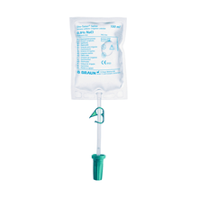 A 100 ml bag of saline solution 0.9% NaCl from the brand B. Braun Deutschland GmbH & Co. KG is hung with a green plastic hook. The B.Braun Uro-Tainer® NaCl is designed for intravesical instillation and carries various medical information and symbols on its front.