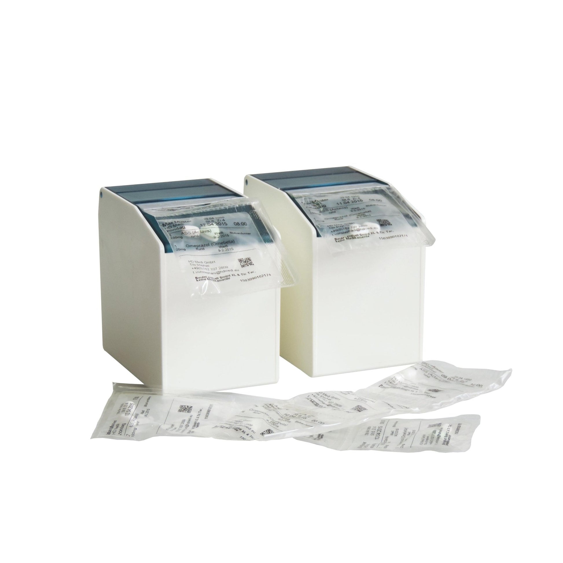 Two white Novocal blister box dispensers (1 flexible front flap, 2 rear magnetic strips, 80 mm, 1 pack) hold sealed medication packages, with additional packs of small products on a white surface against a solid background.