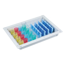 The white Novocal blister module (ABS, 300 x 400 x 50 mm) for 32 residents holds color-coded cylinders - yellow, red, blue - and features vertical blue dividers on the right side for a space-saving medication storage system.