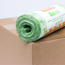 A roll of green compostable waste bags is placed on a cardboard box. The label on the roll is partially visible and bears the print "EMIL DEISS KG (GmbH + Co.)". These 100% compostable bags have a floral design and measure 430 x 500 mm.