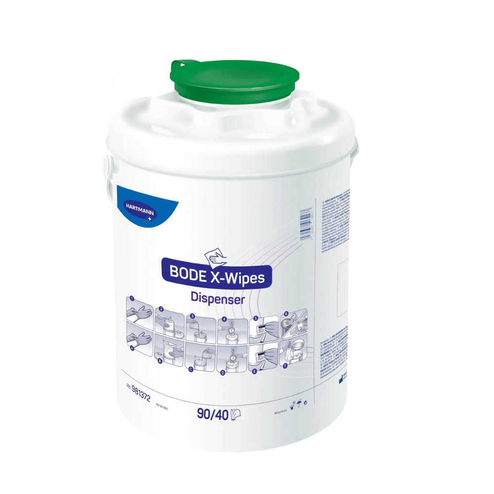 A white plastic dispenser with the inscription "Paul Hartmann AG Hartmann BODE X-Wipes Disinfection Dispenser" with a green lid and blue text, containing usage instructions and diagrams on the sides. The container is placed in front of a plain