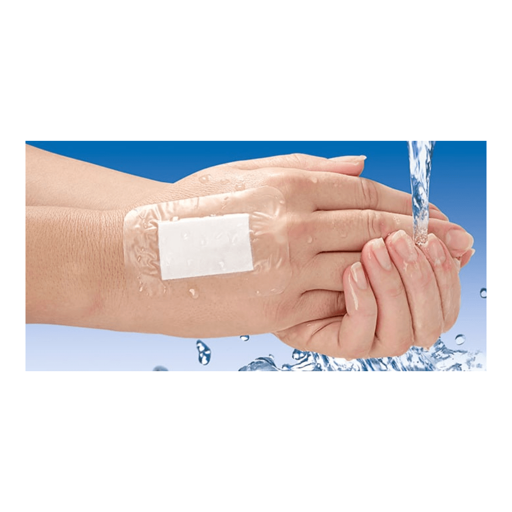 A transparent Hartmann Cosmopor® Waterproof wound dressing, waterproof, 7.2 x 5 cm | Pack (5 pieces) by Paul Hartmann AG is applied to the back of the hand. Water is poured over the dressing, highlighting its waterproof property. The background is a gradient of blue and white.
