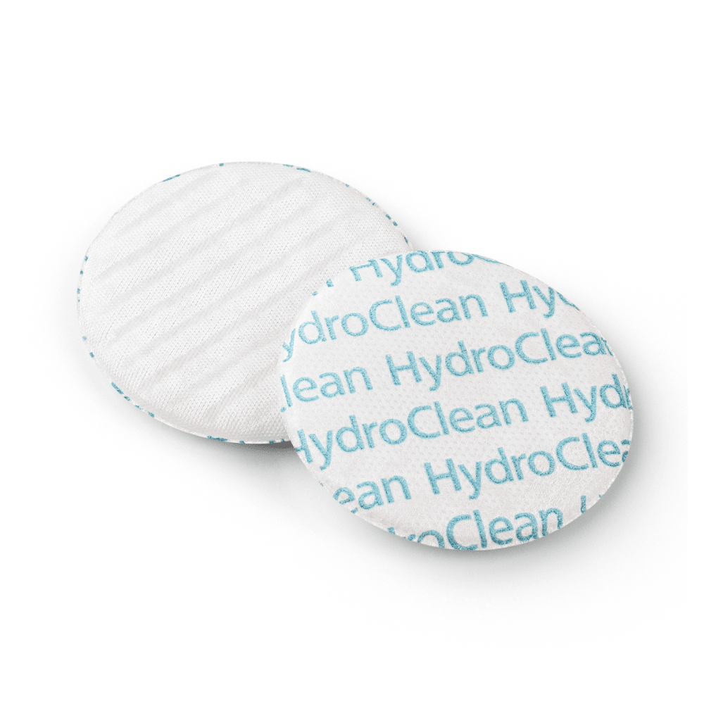 Two round cosmetic pads on a white background, one pad shows the text pattern 'Paul Hartmann AG HydroClean® wound dressing' in blue, the other pad shows a flat surface.