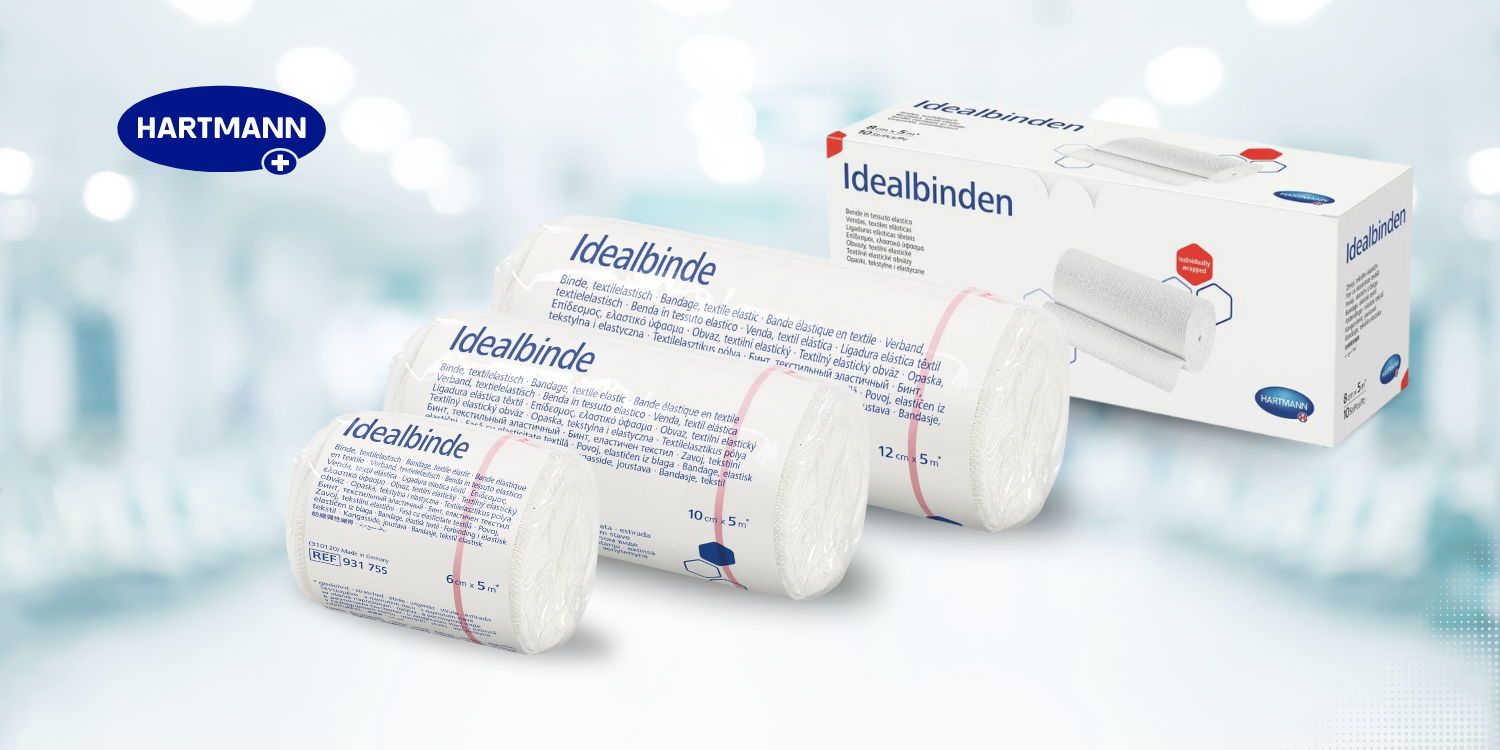 Vor einem hellblauen, unscharfen Hintergrund sind drei gerollte medizinische Binden vor ihrer Verpackung zu sehen. Auf den Binden ist der Name „Idealbinde“ aufgedruckt und in der oberen linken Ecke befindet sich ein „Hartmann“-Logo.