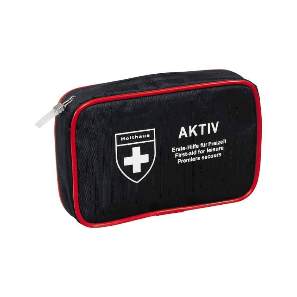 A compact black first aid kit with red trim and zipper, a white cross logo, and the texts “Holthaus Medical AKTIV” and “Erste-Hilfe für Freizeit / First-aid for Leisure / Premiers secours” on the front. Perfect for on the go and at home.