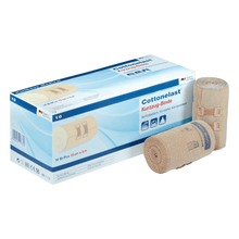 In the picture, there is a box labeled „Holthaus Cottonelast® Short-stretch Bandage“ with two rolled bandages included. The box contains 10 pieces of short-stretch compression bandages measuring 10 cm x 5 m. These medical products from Holthaus Medical GmbH & Co. KG are made of 100% cotton and are crafted from beige fabric with blue seams.