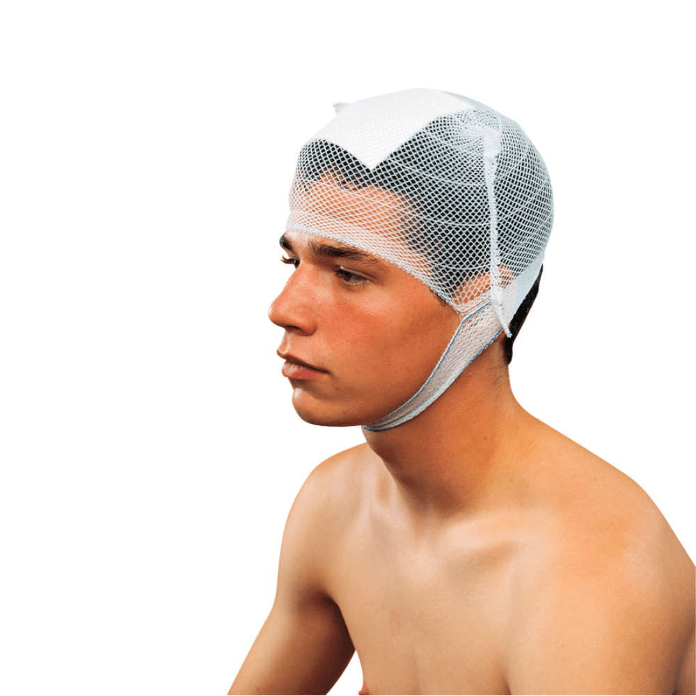 A young person is visible from the shoulders up, looking to the left. They are wearing a Holthaus Ypsinetz head bandage cap by Holthaus Medical GmbH & Co. KG, which is fastened with straps under the chin. The person appears to have short dark hair and is standing shirtless in front of a white background.