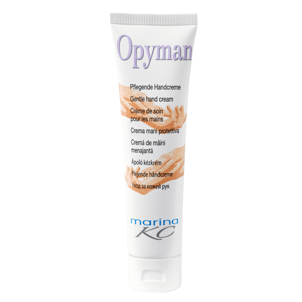 A white standing tube of Kiehl Opyman Nourishing Hand Cream (100 ml) from Johannes Kiehl KG with a hand illustration and multilingual text provides intensive moisture; "marina KC" is printed on the bottom.