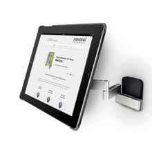 A Novocal tablet holder variant 1 (for tablets 7-12 inches, swivel up to 180°) is mounted on a silver wall bracket with a swivel arm; on the tablet, a website with "novocal" as the heading can be seen.