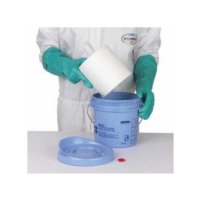 A person with green gloves and a white suit places a roll of Kimtech® Wettask™ wipes into a blue Kimberly-Clark GmbH wiper dispenser bucket; the lid and the red cap are lying on the table next to it.